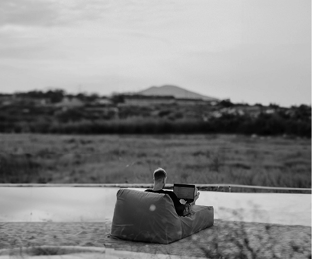 Pessoa deitada em um sofá mexendo no computador