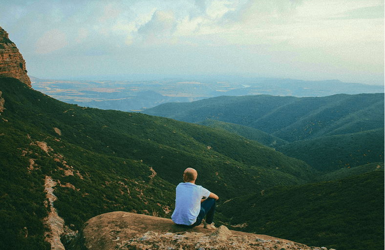 Homem sentando em montanha
